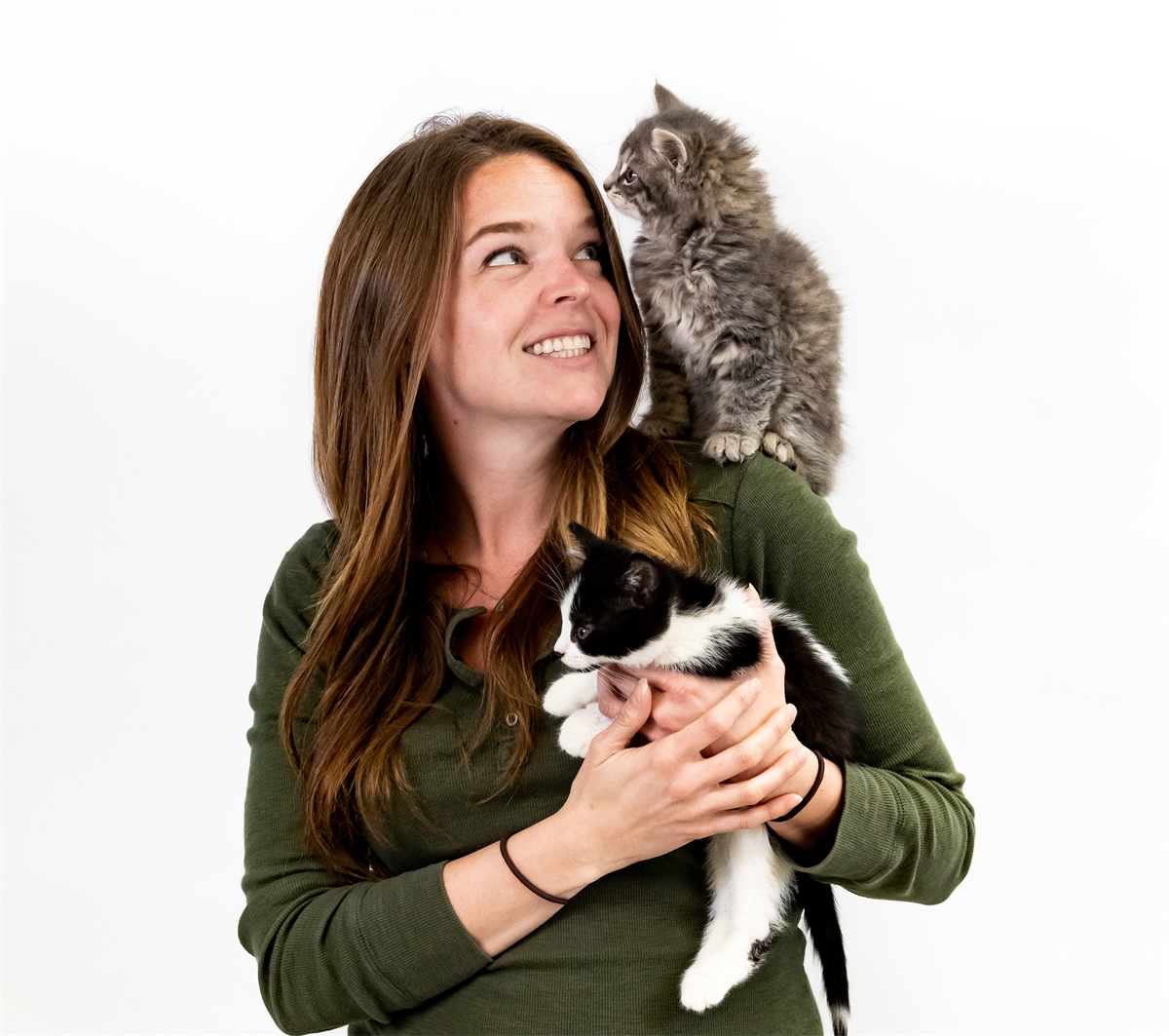 Dr. Ellis holding a black and white kitten while a grey kitten perches on her shoulder